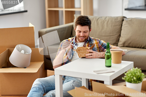 Image of smiling man eating takeaway food at new home