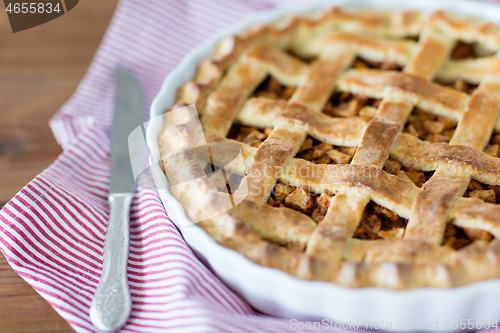 Image of close up of apple pie in baking mold and knife