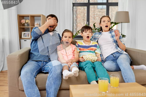 Image of scared family with popcorn watching horror on tv