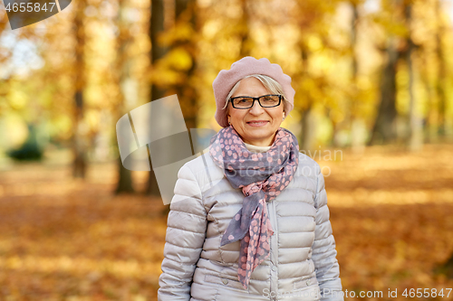 Image of portrait of happy senior woman at autumn park