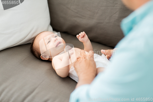 Image of middle aged father changing baby\'s diaper at home