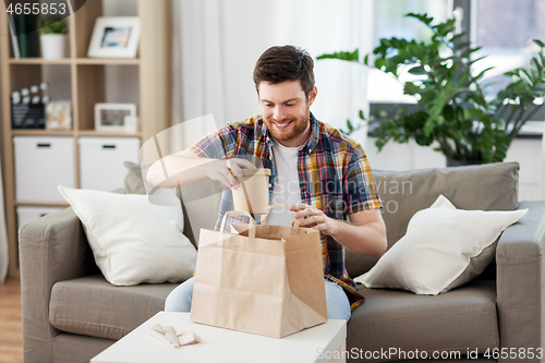 Image of smiling man unpacking takeaway food at home