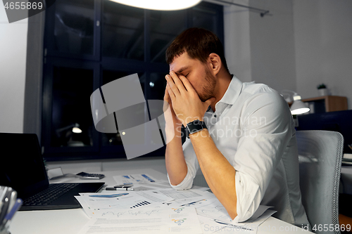 Image of tired businessman working at night office