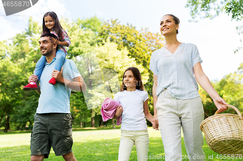 Image of family with picnic basket walking in summer park