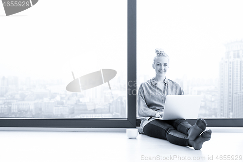 Image of woman drinking coffee and using laptop at home