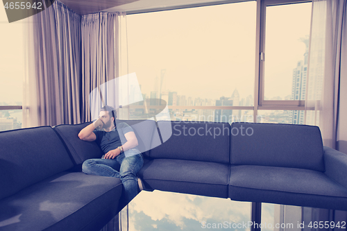 Image of young casual man using a mobile phone at home