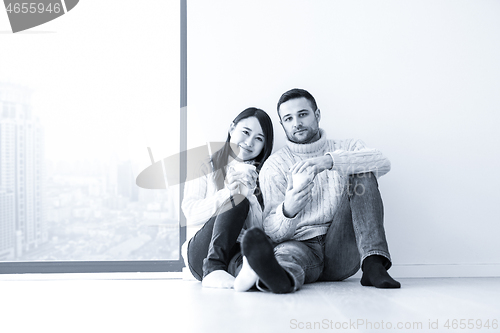 Image of multiethnic couple enjoying morning coffee by the window