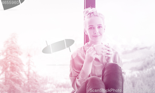 Image of woman drinking coffee and using laptop at home