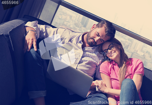 Image of couple relaxing at  home using laptop computers