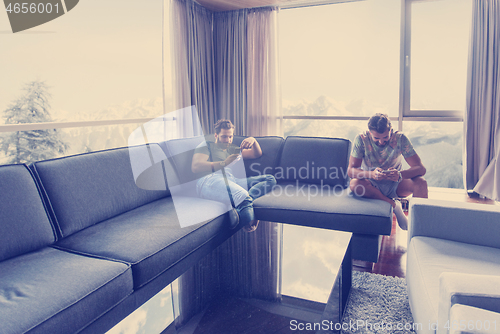 Image of two young men using a mobile phones  at home