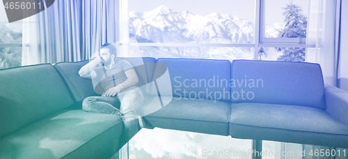 Image of young casual man using a mobile phone at home