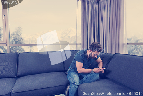 Image of young casual man using a mobile phone at home