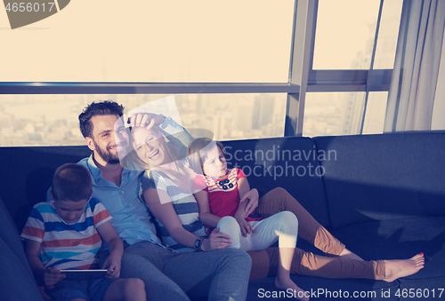 Image of happy young couple spending time with kids at home