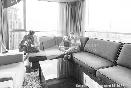 Image of two young men using a mobile phones  at home