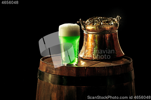 Image of The wooden background with lots of gold coins and a large mug of beer with a green bow.