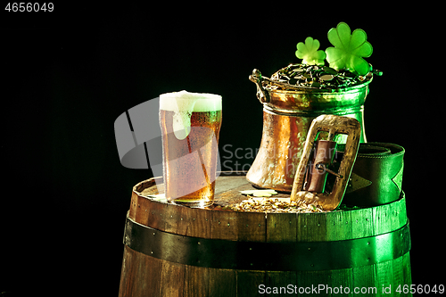 Image of The wooden background with lots of gold coins and a large mug of beer with a green bow.