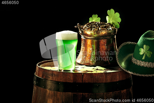 Image of The wooden background with lots of gold coins and a large mug of beer with a green bow.