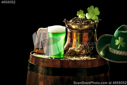 Image of The wooden background with lots of gold coins and a large mug of beer with a green bow.