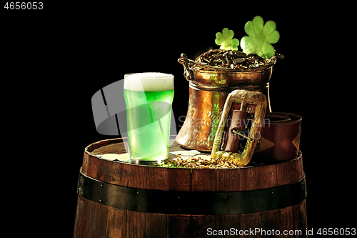 Image of The wooden background with lots of gold coins and a large mug of beer with a green bow.