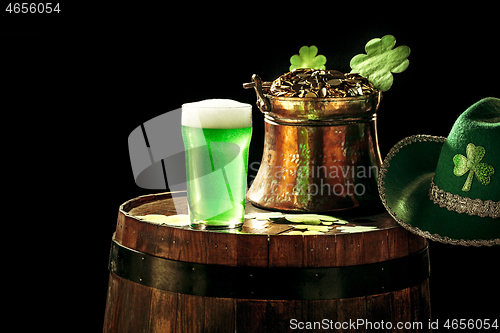 Image of The wooden background with lots of gold coins and a large mug of beer with a green bow.