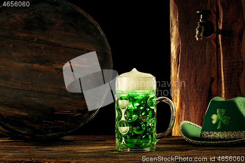 Image of The wooden background with lots of gold coins and a large mug of beer with a green bow.