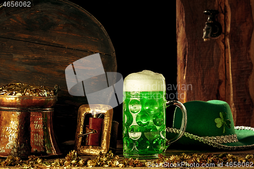 Image of The wooden background with lots of gold coins and a large mug of beer with a green bow.