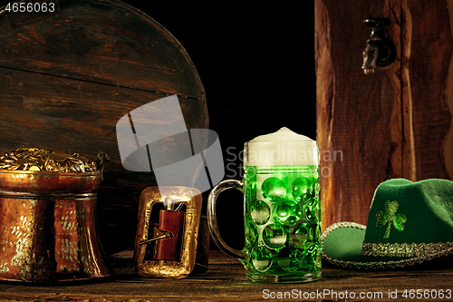 Image of The wooden background with lots of gold coins and a large mug of beer with a green bow.