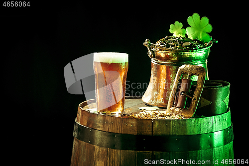 Image of The wooden background with lots of gold coins and a large mug of beer with a green bow.