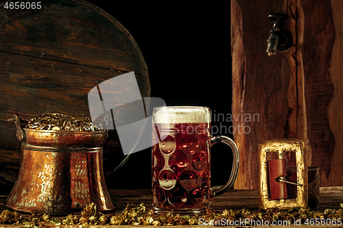 Image of The wooden background with lots of gold coins and a large mug of beer with a green bow.