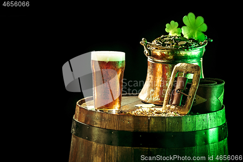 Image of The wooden background with lots of gold coins and a large mug of beer with a green bow.