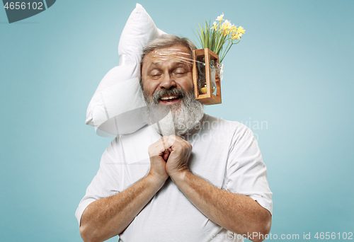 Image of Tired man sleeping at home having too much work. Bored businessman with pillow and hourglass