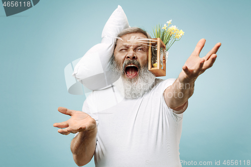 Image of Tired man sleeping at home having too much work. Bored businessman with pillow and hourglass