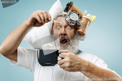 Image of Tired man sleeping at home having too much work. Bored businessman with pillow and hourglass