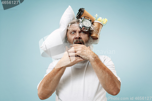 Image of Tired man sleeping at home having too much work. Bored businessman with pillow and hourglass