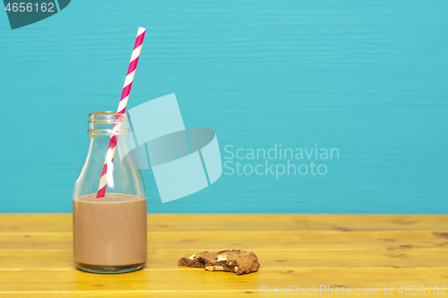 Image of Straw and bottle half full with milkshake, and half-eaten cookie