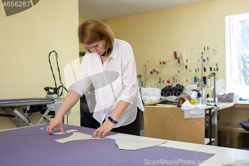 Image of the cutter lays out the patterns on the matter on a large table in the workshop