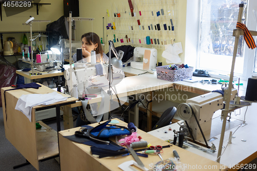 Image of girl with a bored and dejected look at the workplace in a sewing workshop