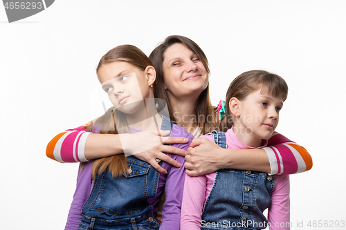 Image of Mom happily hugs children, children turned away from mom