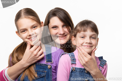 Image of Mom cheerfully holds the children by the chin and looks in the frame