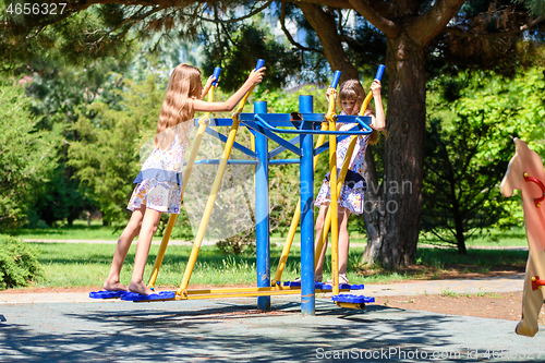 Image of Two girls warm up on exercise machines in the park
