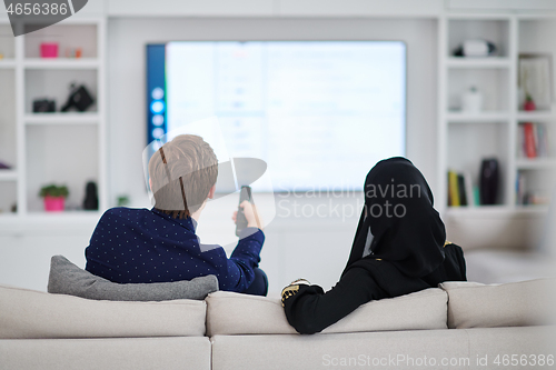 Image of young muslim couple watching TV together