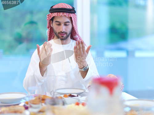Image of arabian man making traditional prayer to God before iftar dinner