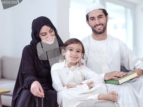 Image of muslim family reading Quran and praying at home