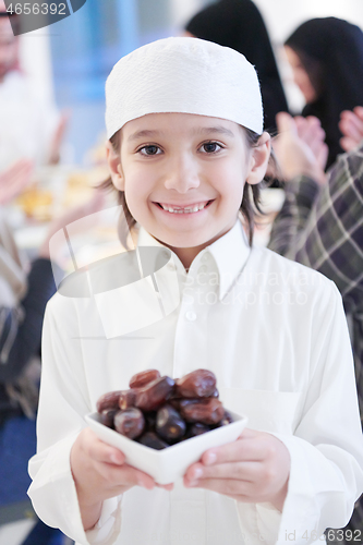 Image of little muslim boy holding a plate full of sweet dates