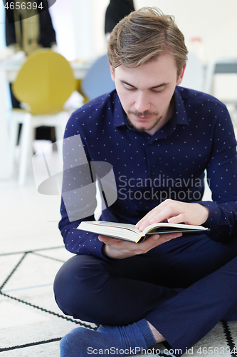 Image of young muslim man reading Quran at home