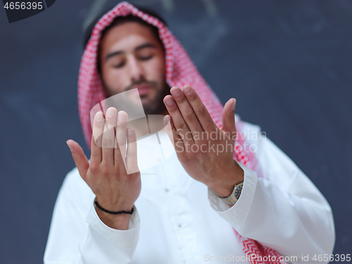 Image of arabian man making traditional prayer to God, keeps hands in pra