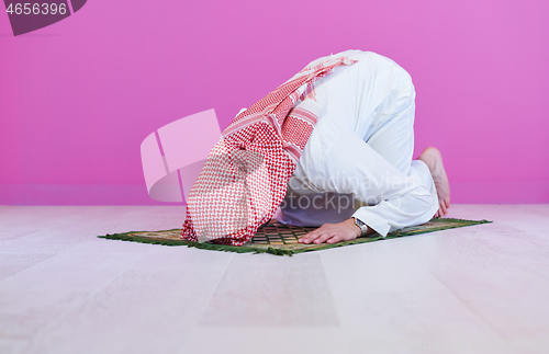 Image of young arabian muslim man praying on the floor at home