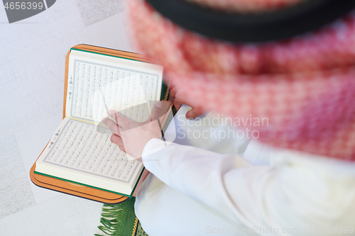 Image of arabian muslim man reading Quran at home