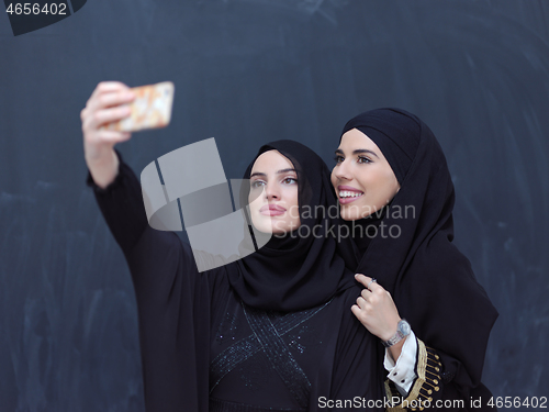 Image of muslim women taking selfie picture in front of black chalkboard