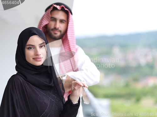 Image of portrait of beautiful arabian couple standing on balcony